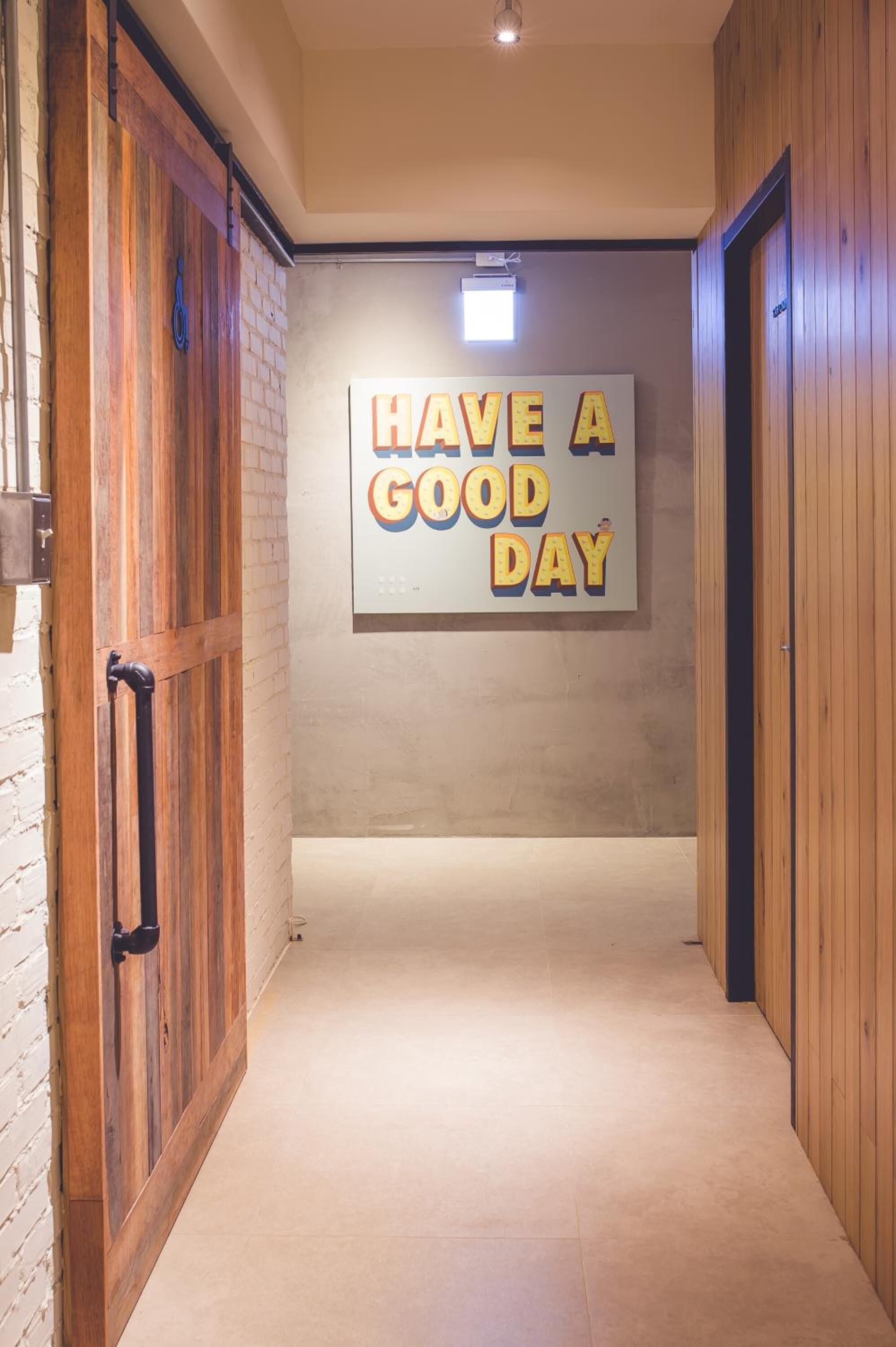 A hallway with a motivational sign saying "HAVE A GOOD DAY" and wooden walls.