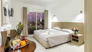 Une chambre d’hôtel avec un lit, une table de chevet et une table pour le petit-déjeuner, avec des fruits et une bouteille de champagne.