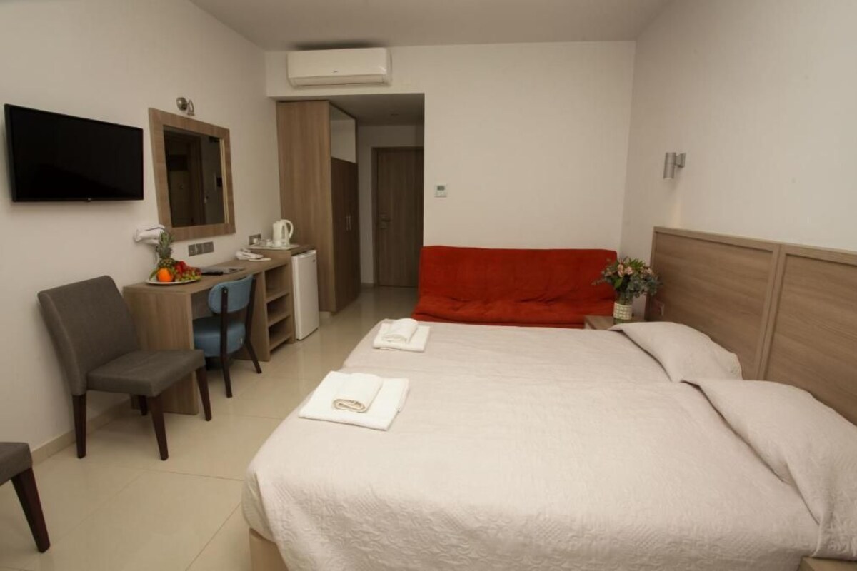 Ein Hotelzimmer mit Bett, Schreibtisch mit Stuhl, Fernseher und Spiegel.