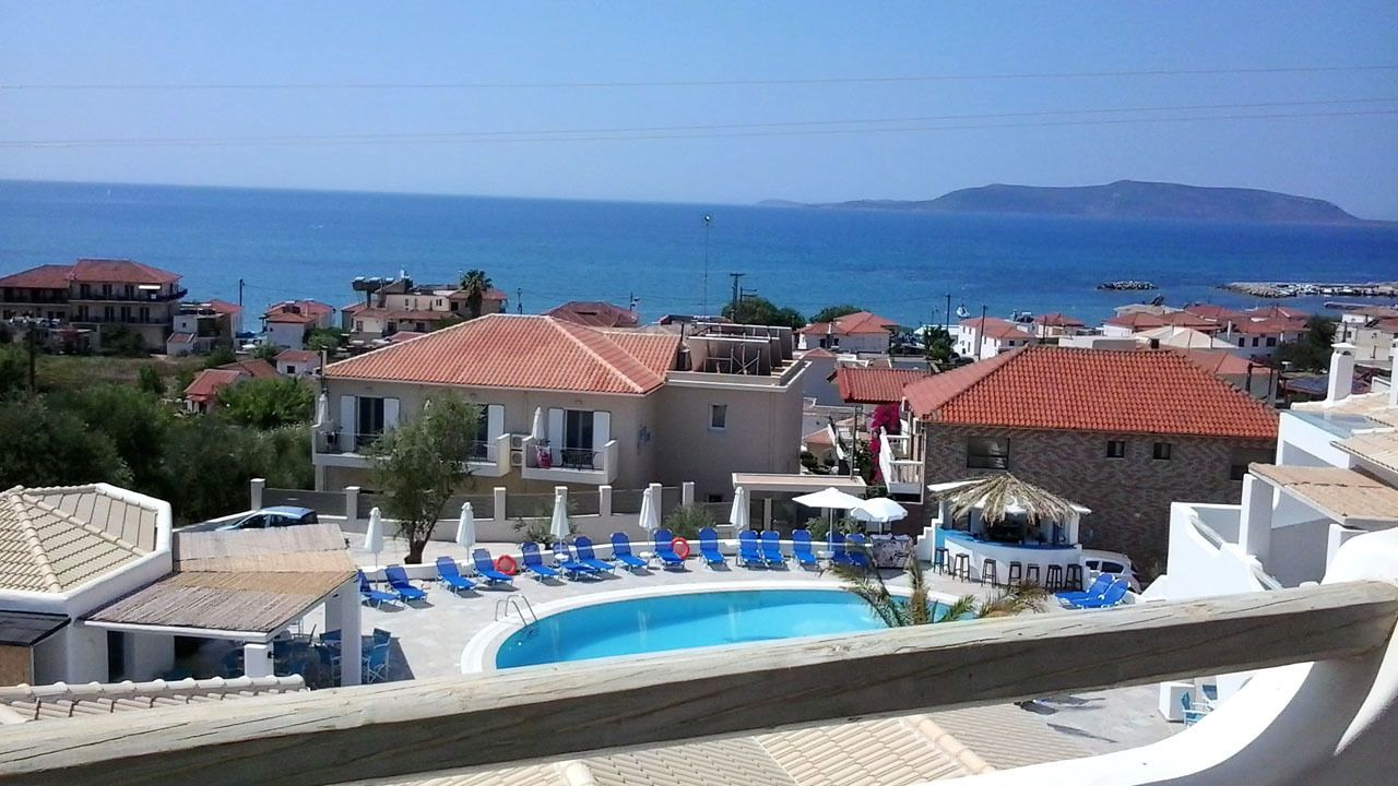 A resort with a swimming pool, lounge chairs, and a view of the sea.