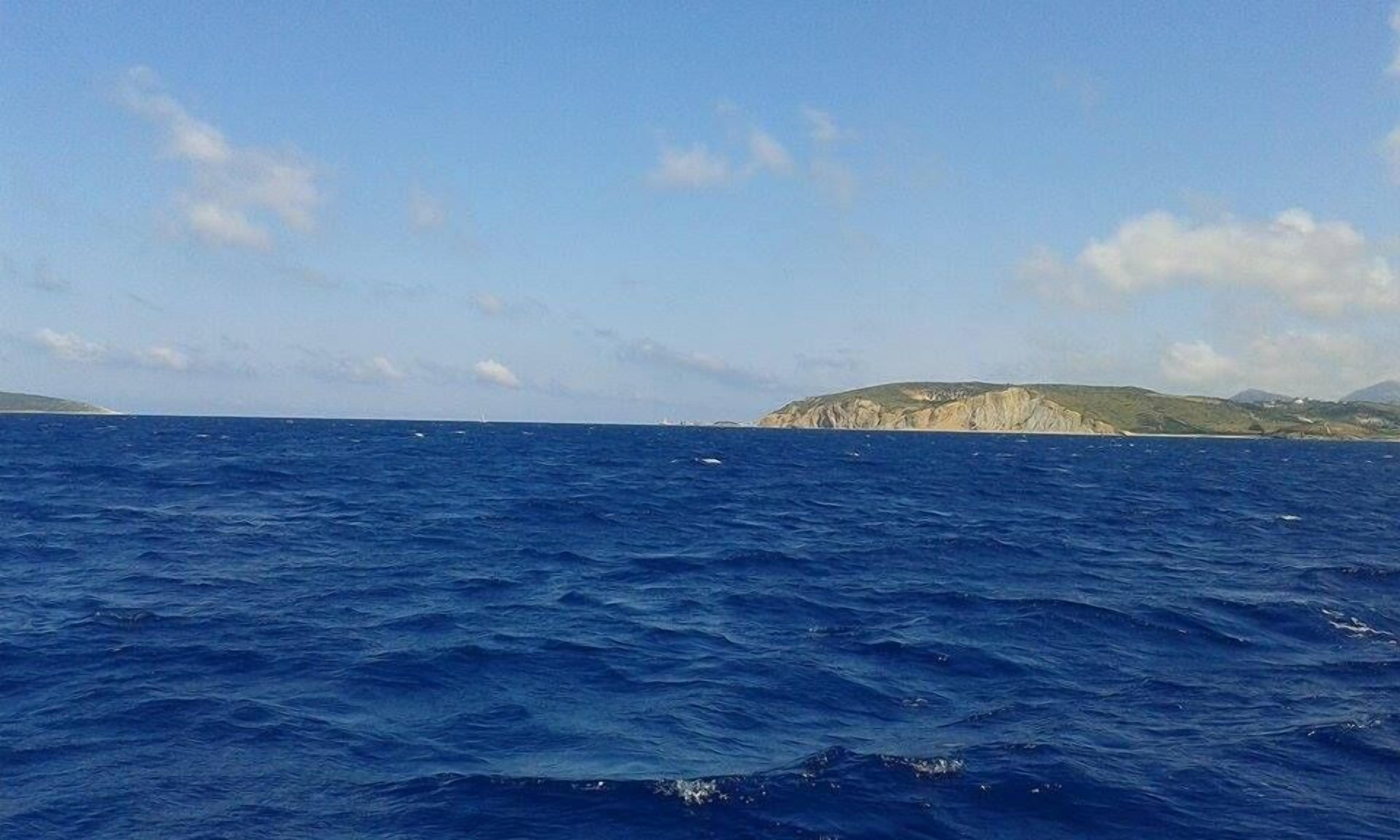 Vista del mar con una costa rocosa distante.