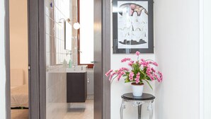 A modern bathroom with a large mirror, a sink, and a potted plant on a small table. - Apartop (Rome)
