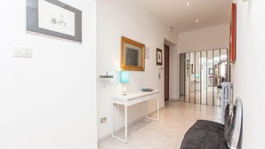 A hallway with a white desk, a lamp, and a mirror on the wall. - Apartop (Rome)