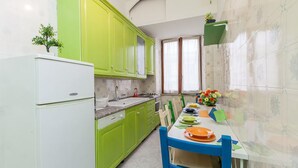 A kitchen with green cabinets, a white refrigerator, a sink, and a dining table with chairs. - Apartop (Rome)