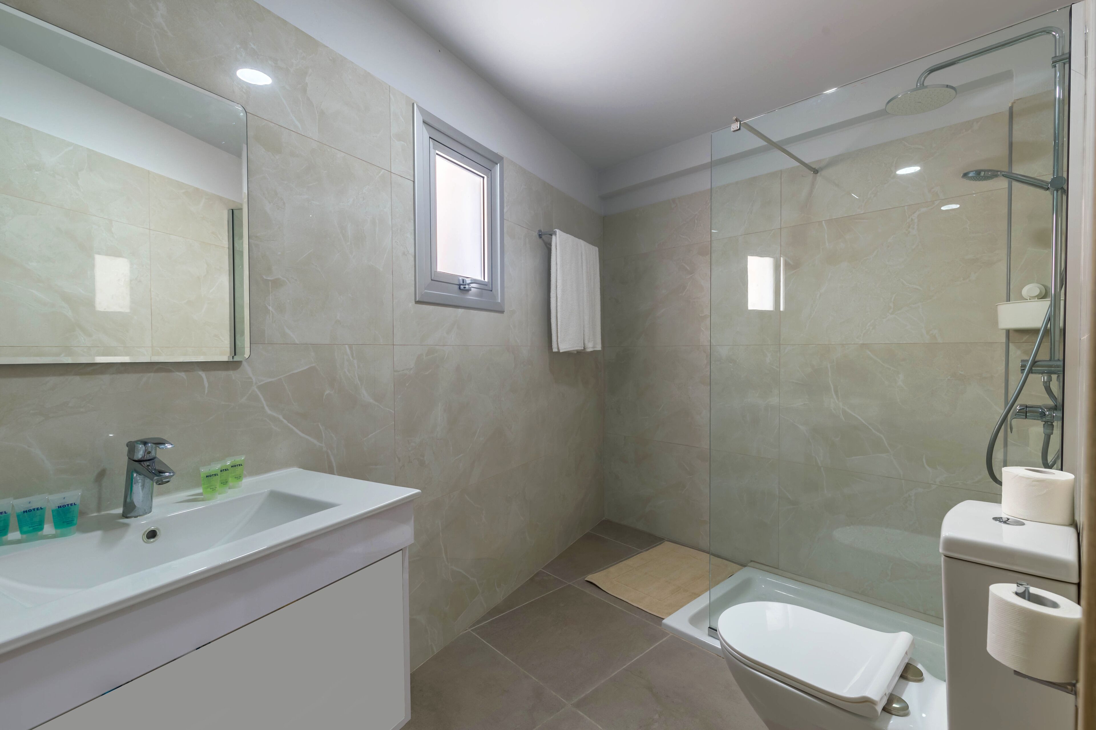 A modern bathroom with a sink, mirror, shower, and toilet.