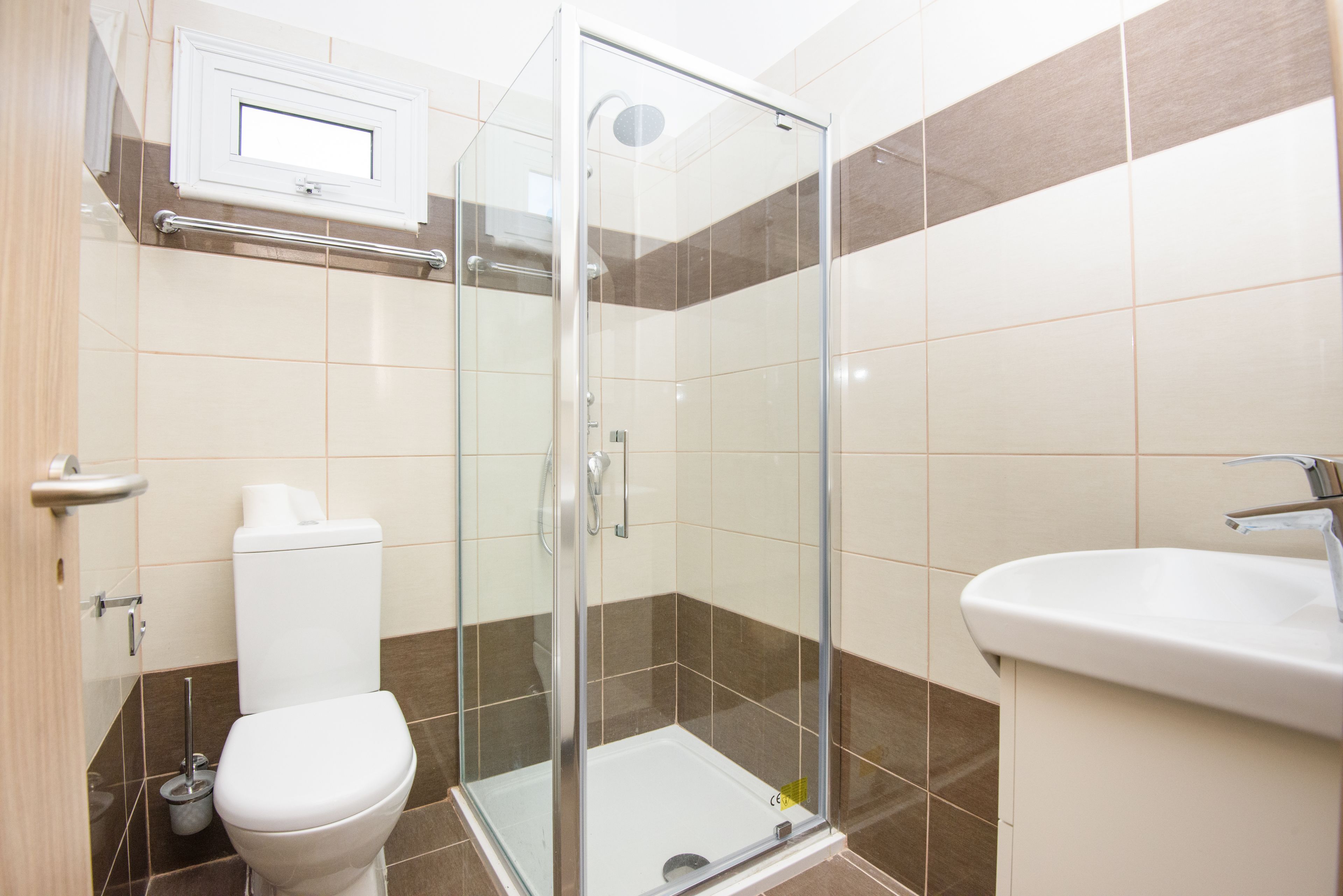 A modern bathroom with a glass-enclosed shower, a white sink, and a toilet.