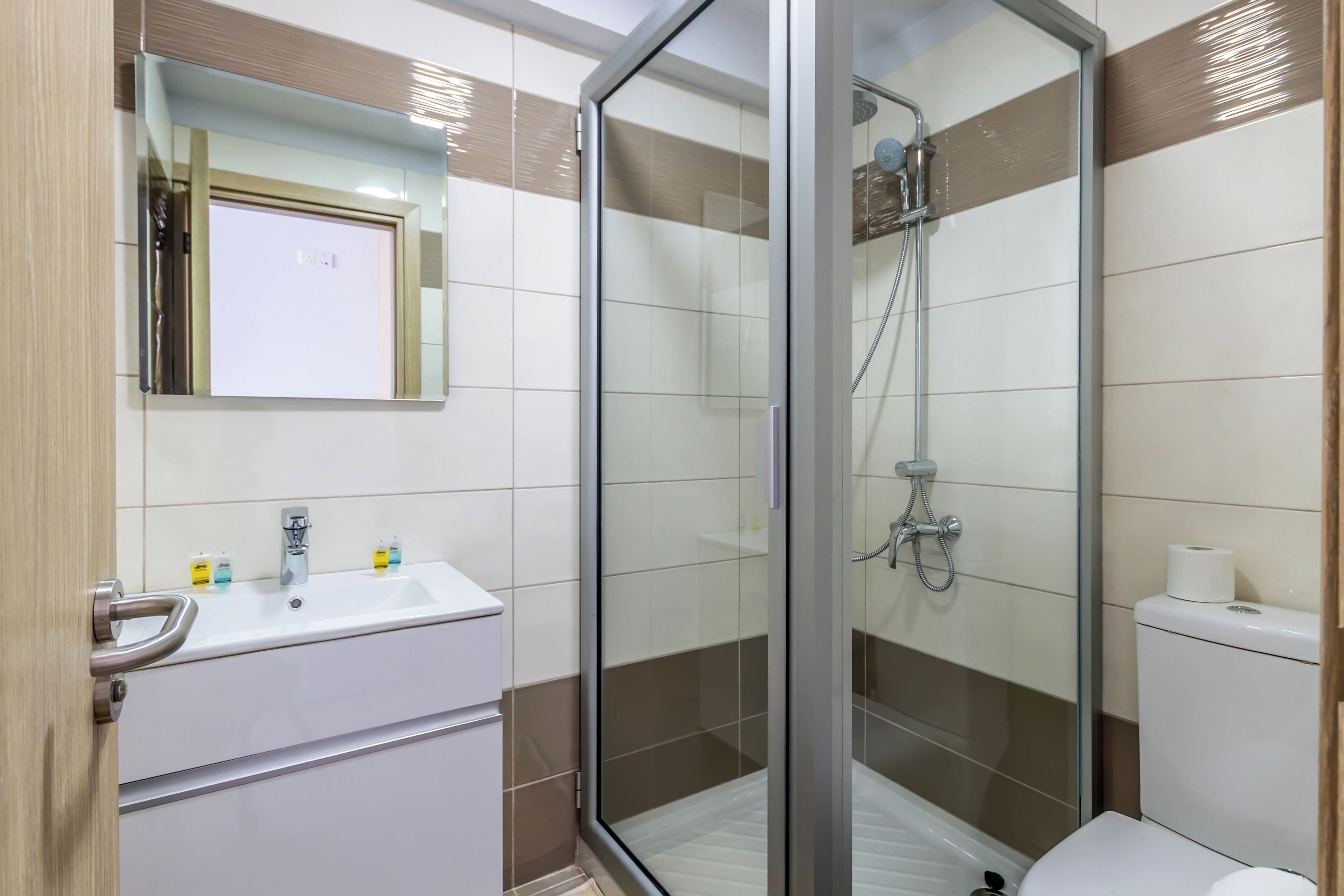 A modern bathroom with a glass-enclosed shower, a sink with a mirror, and a toilet.