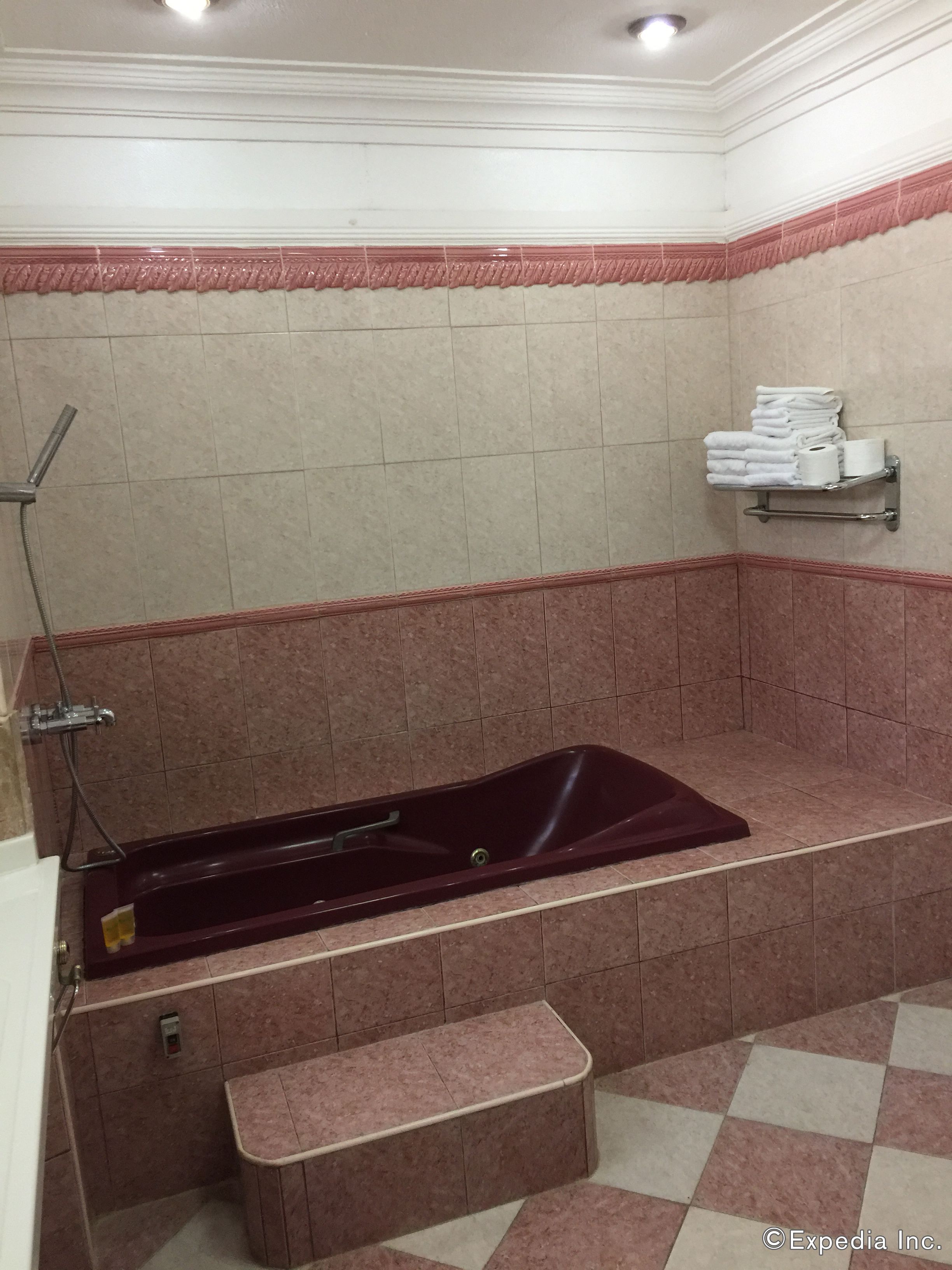 Un baño con una bañera grande, ducha y un perchero con toallas.