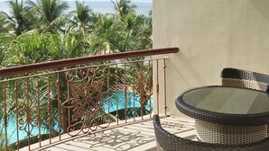 A balcony with a view of palm trees and a swimming pool. - Bohol Tropics Resort (Tagbilaran)