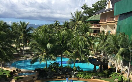 A resort pool with a tropical theme, including a dolphin statue and the words "BOHOL Tropics" on the water.