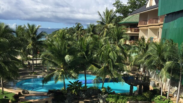 A resort pool with a tropical theme, including a dolphin statue and the words "BOHOL Tropics" on the water. - Bohol Tropics Resort (Tagbilaran)