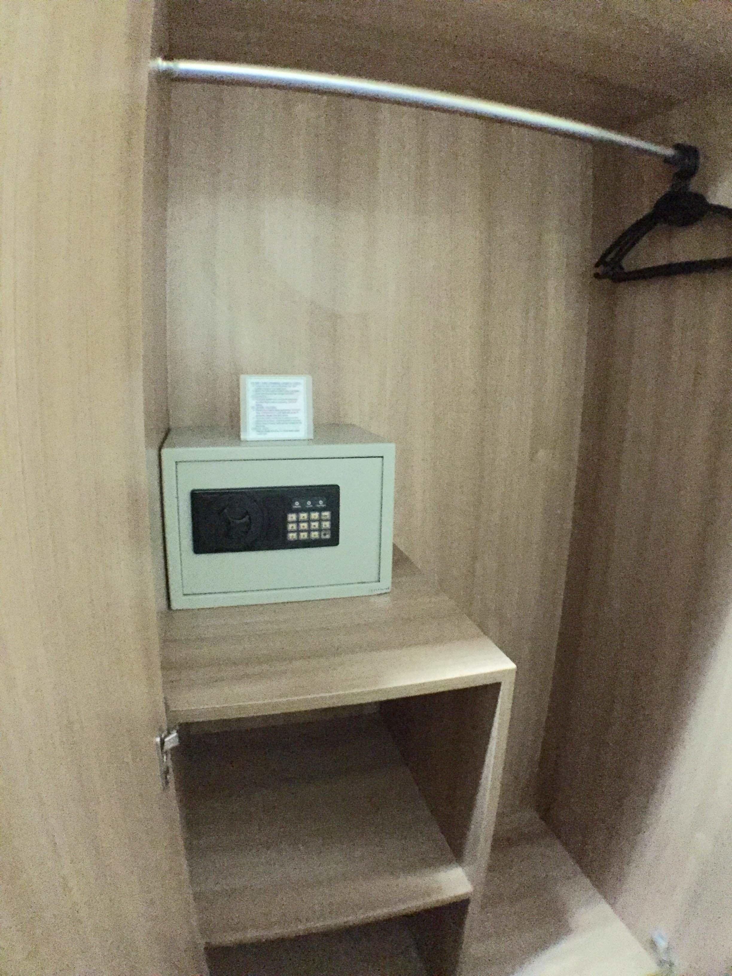 Petit espai tancat amb una barra de metall i un dispositiu electrònic blanc sobre una prestatgeria.