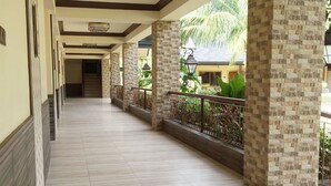 A corridor with tiled flooring, decorative columns, and a railing overlooking a garden. - Bohol Tropics Resort (Tagbilaran)
