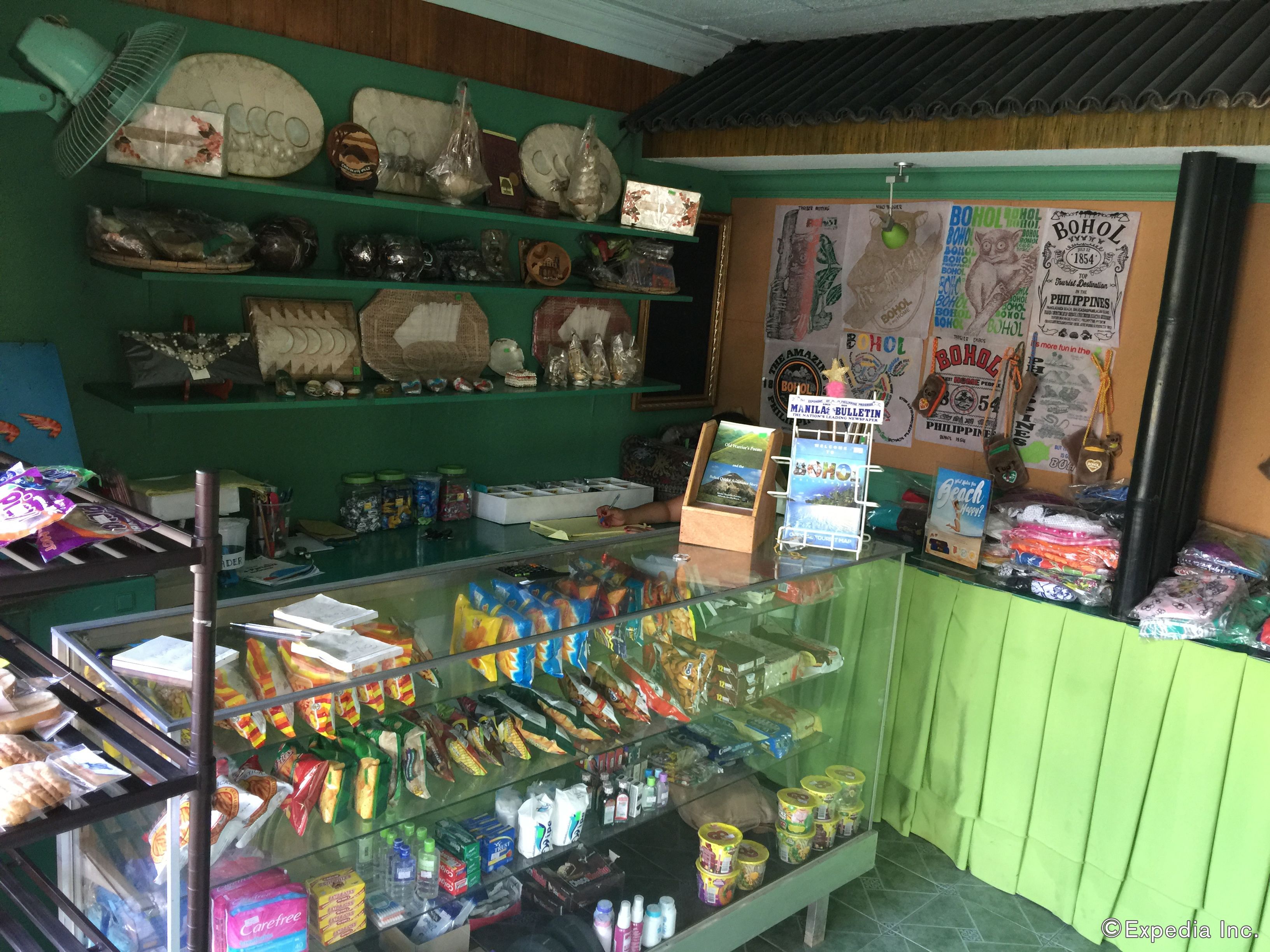 A store with shelves of snacks, a glass display case with packaged goods, and a wall with various posters.