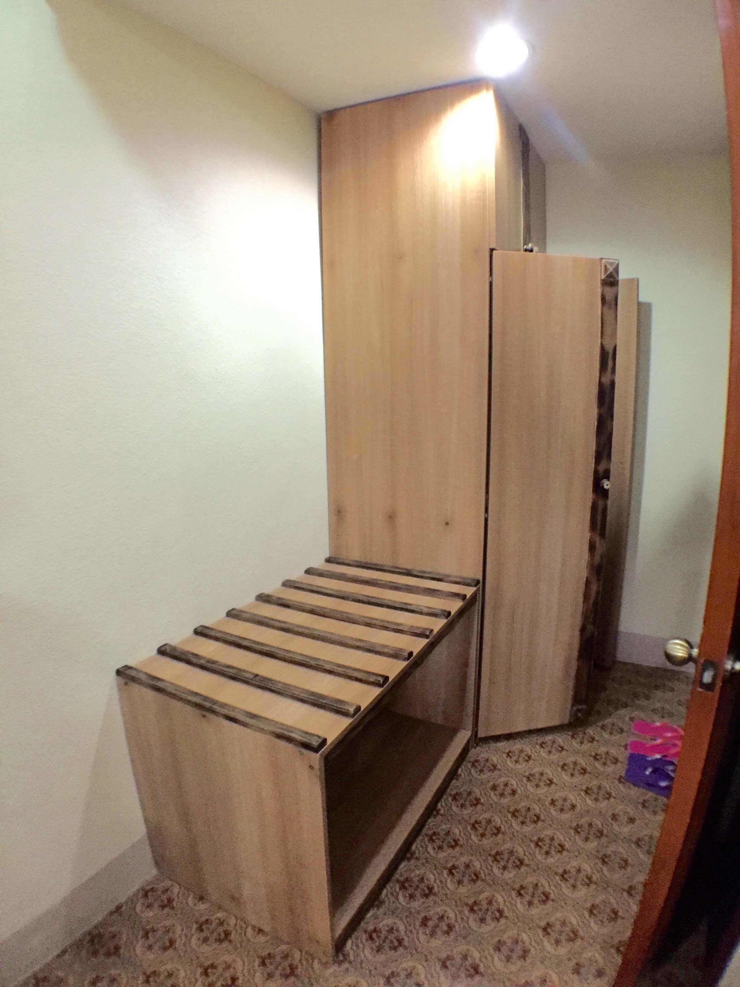 Une petite pièce avec un banc en bois, une armoire et un tapis à motifs.