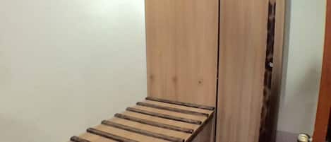 Une petite pièce avec un banc en bois, une armoire et un tapis à motifs.