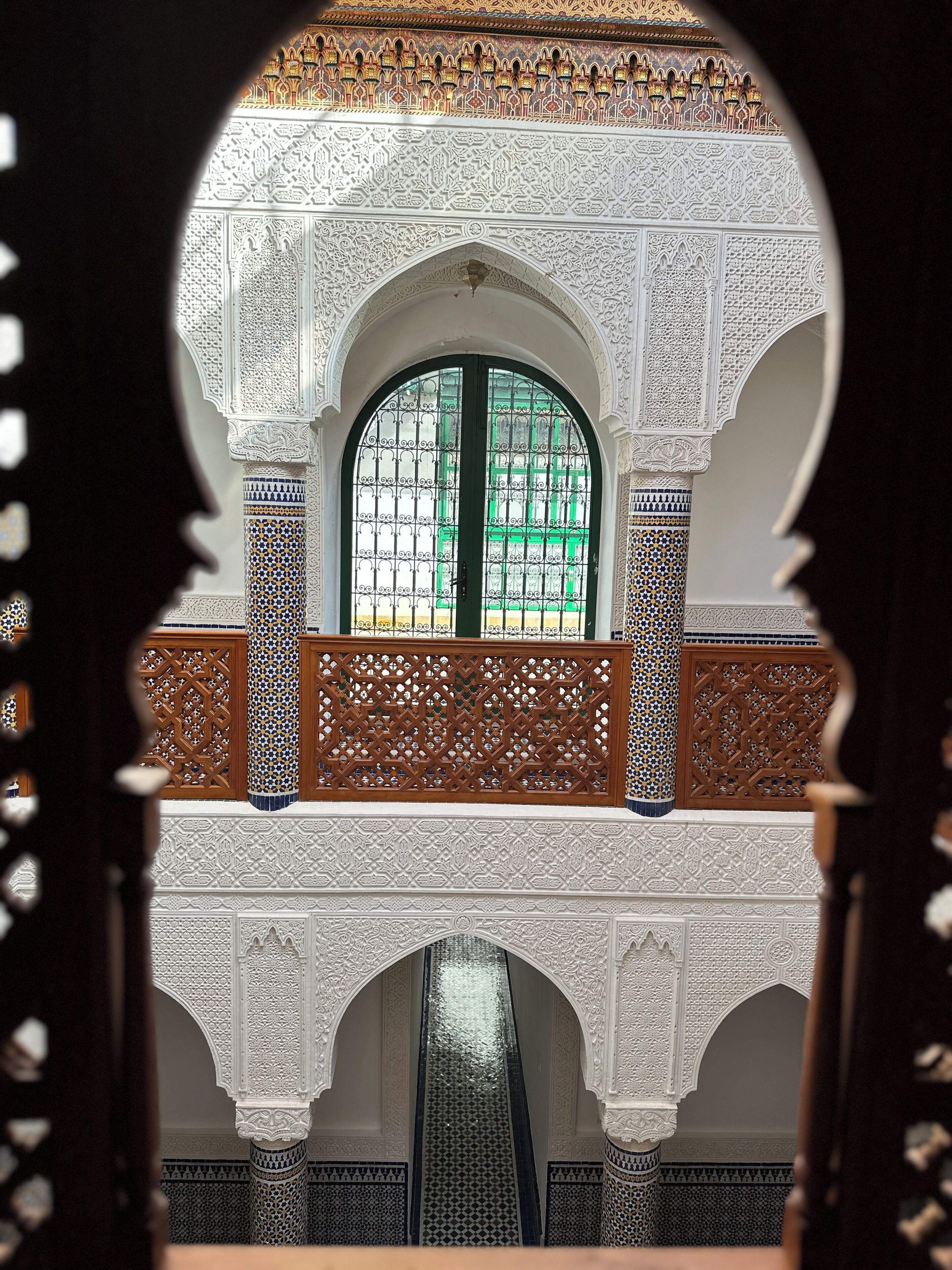 Ein kunstvoller architektonischer Blick mit aufwendigen Fliesenarbeiten und einem grün gerahmten Fenster.