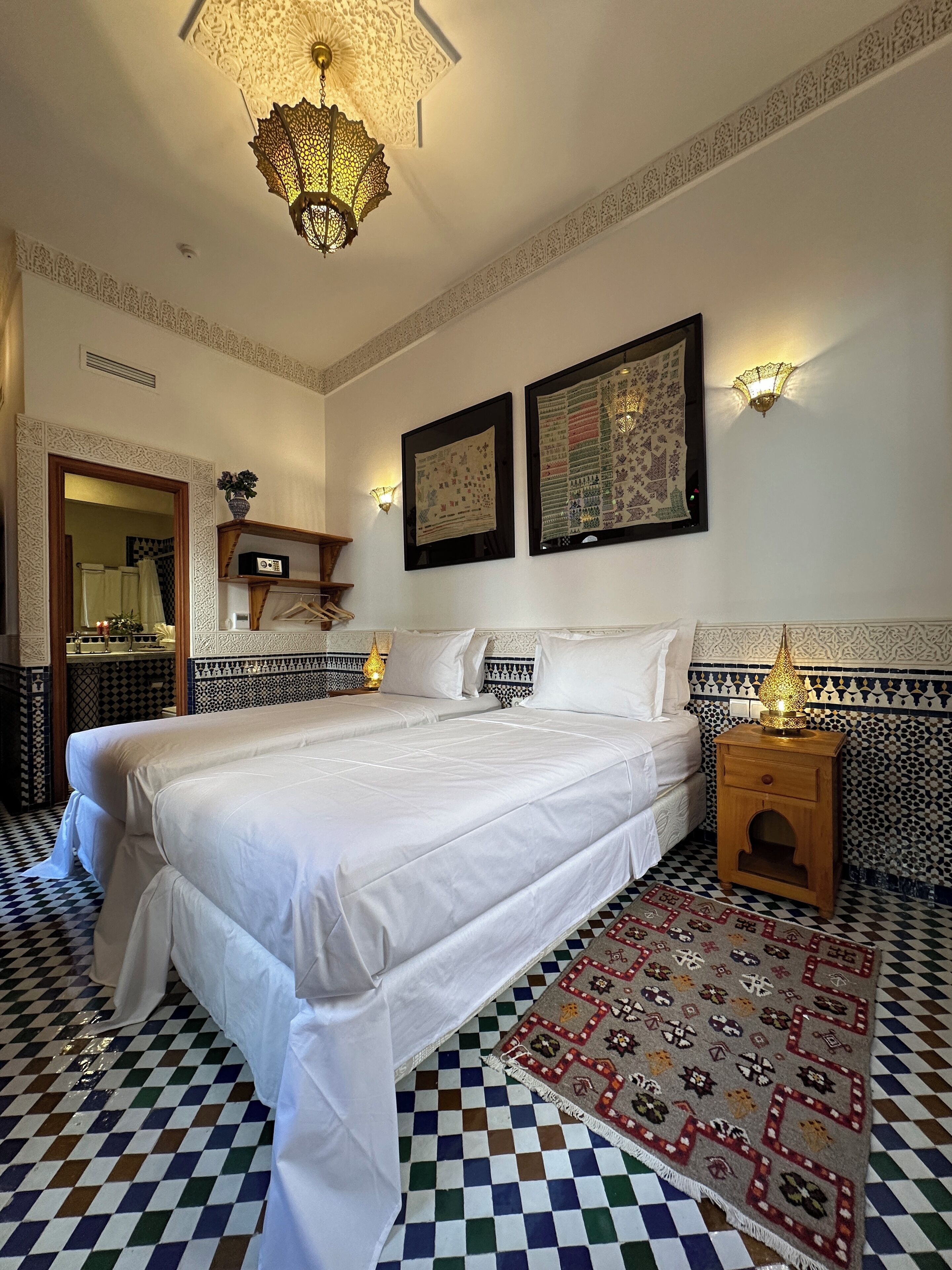 Une chambre avec un grand lit, un tapis à motifs et des appliques murales décoratives.