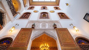 Un interior ornamentado con detalles arquitectónicos intrincados, un candelabro y varios ventanales en arco.