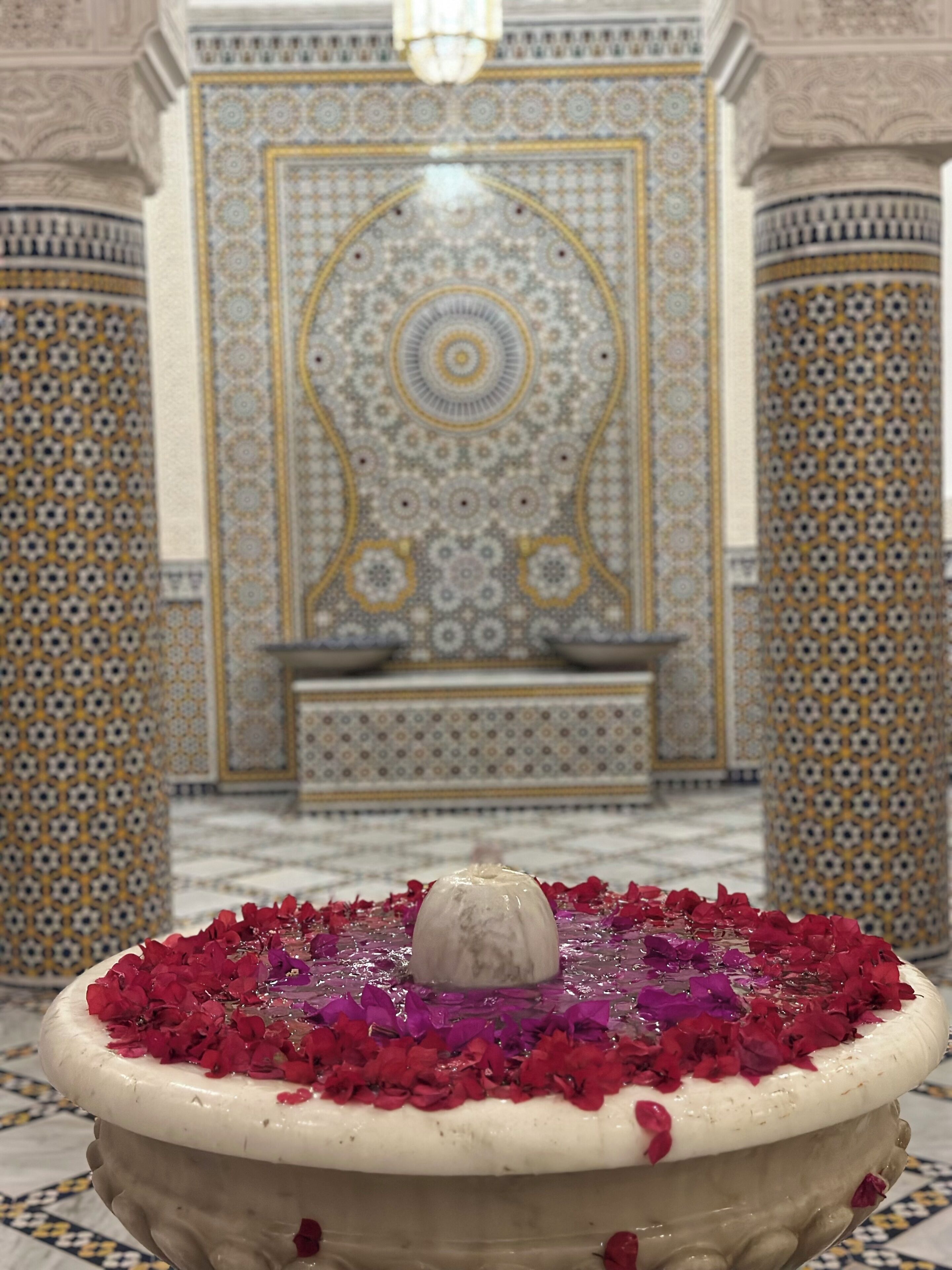 Una font amb flors vermelles en una habitació amb parets i columnes amb dibuixos.