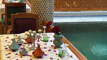 Una mesa de comedor decorada con elementos tradicionales marroquíes, incluyendo una tetera, una jarra y un florero con una rosa.