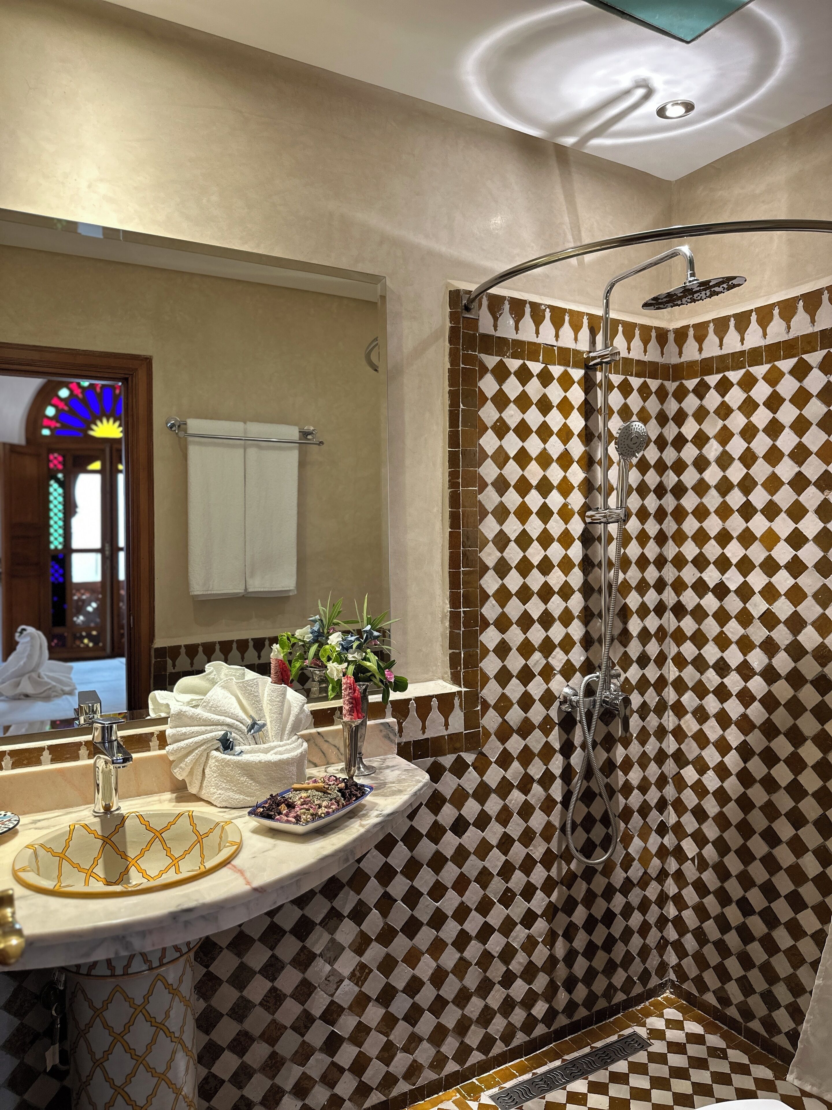 Une salle de bain avec une douche, un lavabo doté d’un plan de toilette en marbre et un miroir.