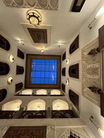 Una habitación con un ventanal grande, techo ornamentado y paredes con diseño.