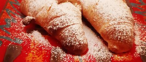 Two pastries dusted with powdered sugar on a red plate with a decorative edge.