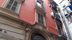 A red building with a black door and a large window. - Casa Mariella (Naples)