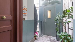 A narrow entrance with a wooden door, a small potted plant, and a sign on the wall. - Casa Mariella (Naples)