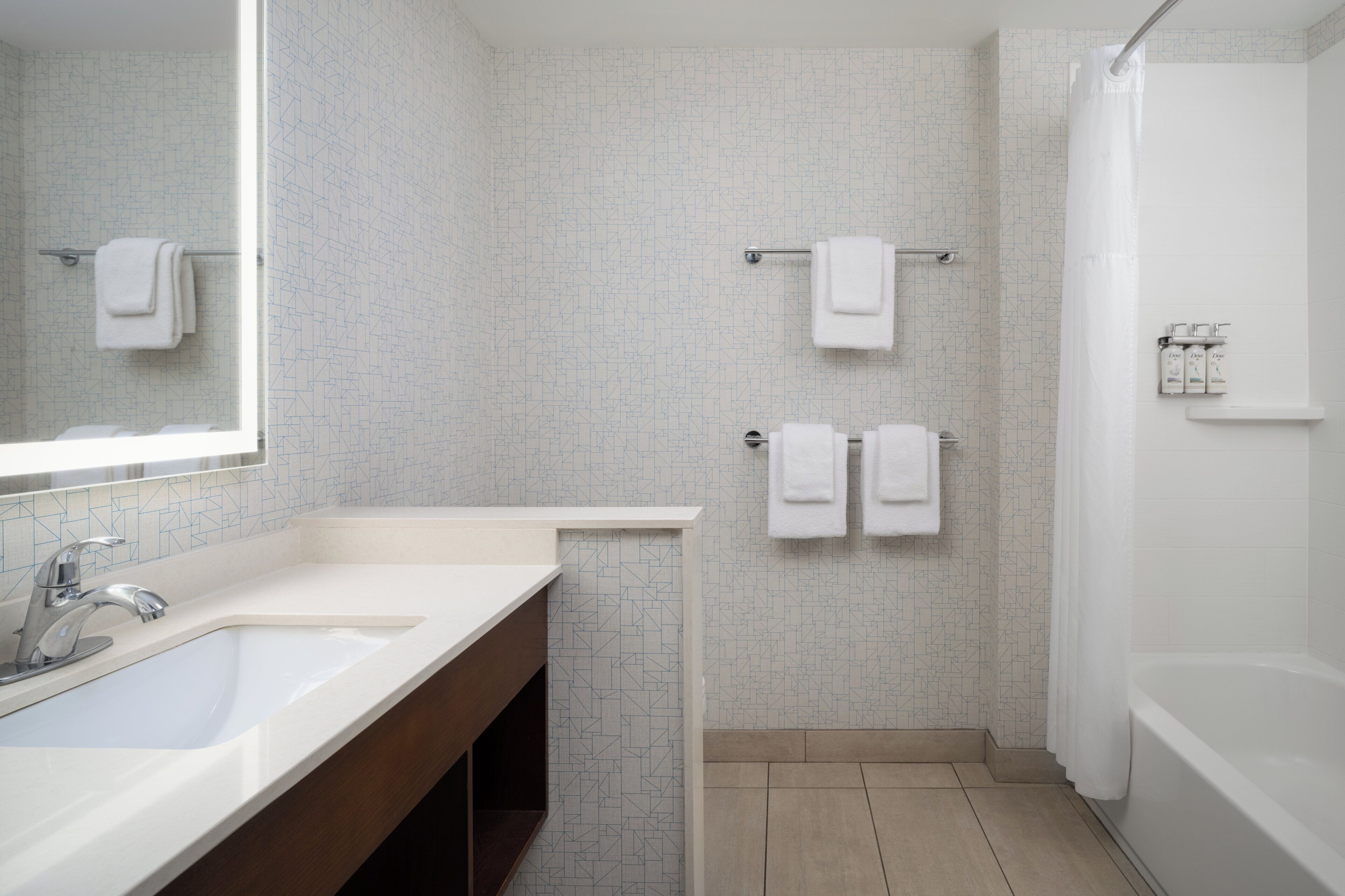 Un baño moderno con lavamanos, espejo y ducha blancos.