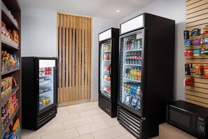 A clean, modern room with a refrigerator, microwave, and vending machine, and a wooden slat wall. - Holiday Inn Express & Suites Trinity by IHG (Trinity)
