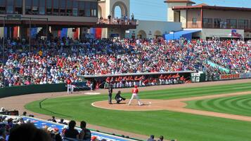 A baseball stadium with a large crowd, a baseball diamond, and a scoreboard.