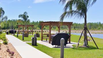 Un patio al aire libre con una pérgola de madera, una parrilla y un banco.