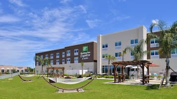 A Holiday Inn Express & Suites hotel with a well-maintained lawn, outdoor seating area, and a hammock.