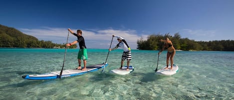 Tres personas en tablas de remo en agua turquesa y transparente.