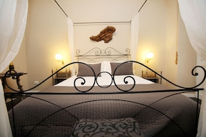 A bed with a headboard, two bedside lamps, and a wall-mounted artwork. - Amica Rome Guest House (Rome)