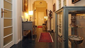 A hallway with a red rug, a desk with a lamp, and a statue on a pedestal. - Amica Rome Guest House (Rome)