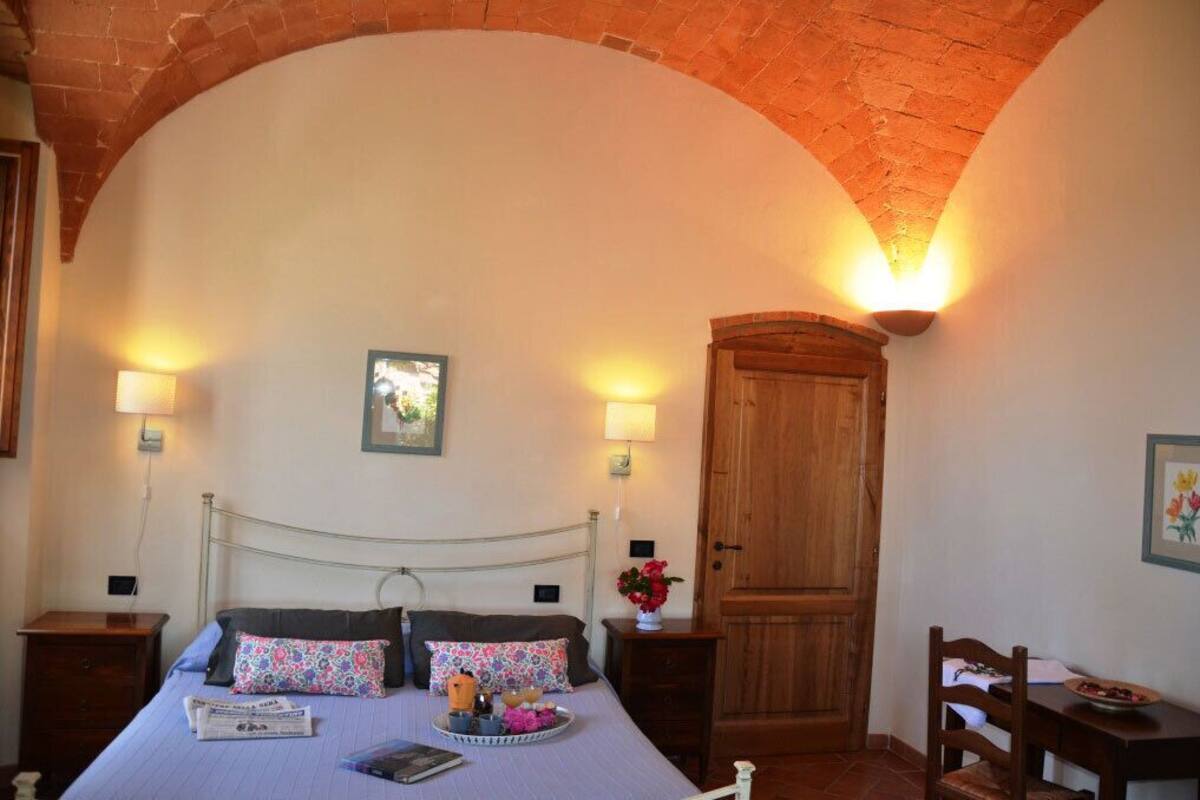 Ein Schlafzimmer mit einem Bett, zwei Nachttischen, einem Holzschrank und einem kleinen Tisch mit Stuhl.