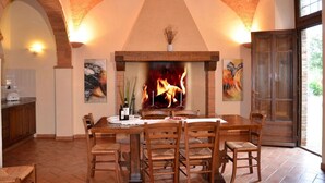 A dining area with a fireplace, wooden chairs, and a table. - Rigone in Chianti (Montaione)