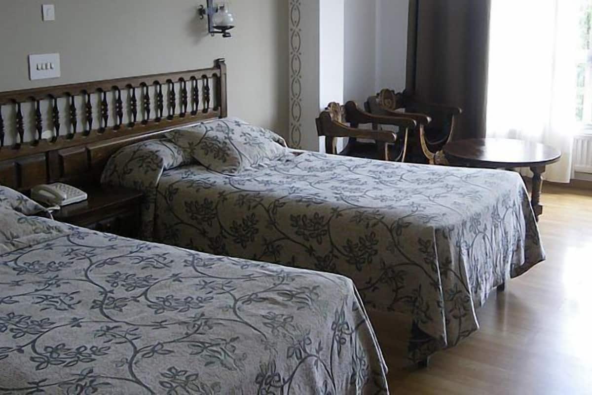 A hotel room with two beds, a small table, and a chair.