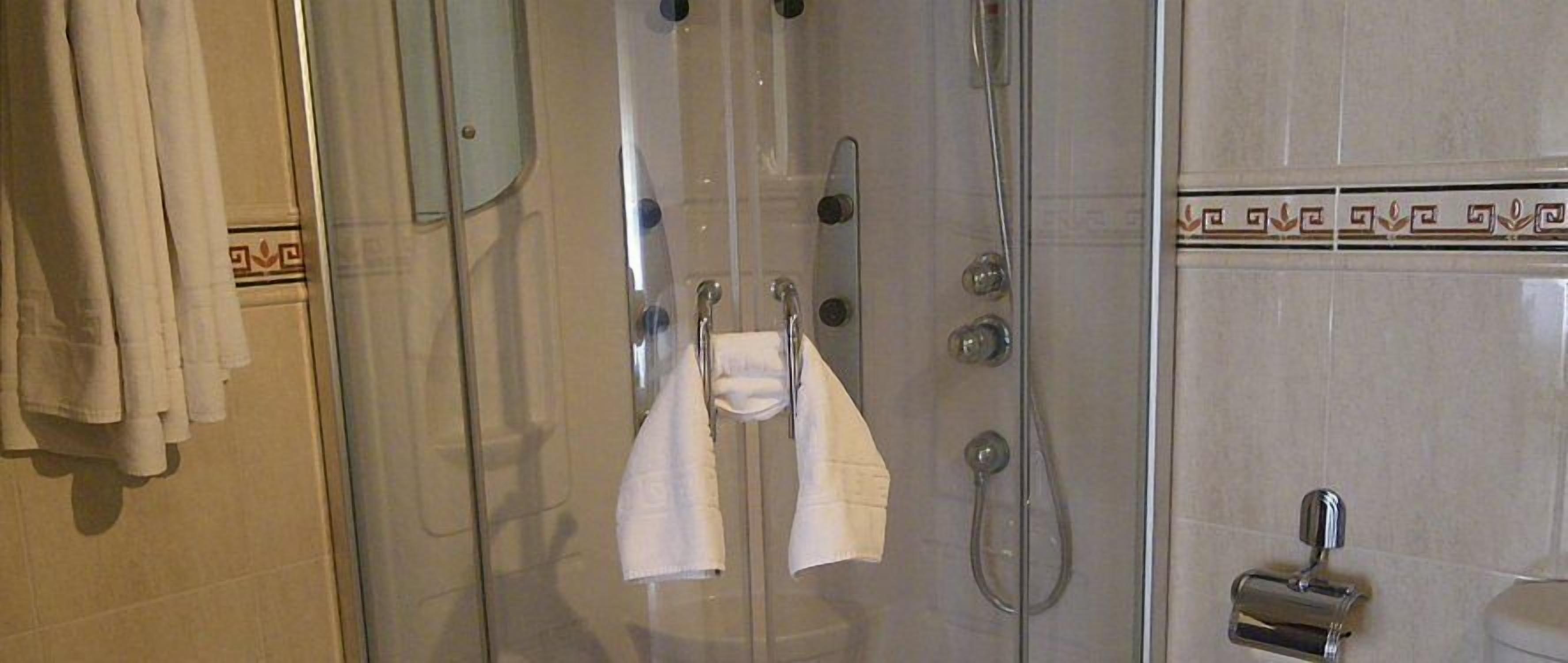 Een douche met een glazen deur, een handdoekhouder en een douchekop.