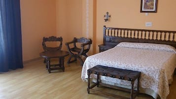 Une chambre à coucher avec un lit en bois, un banc, deux chaises et une petite table.