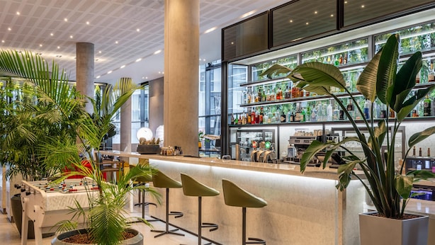 A modern bar area with a foosball table, bar stools, and a well-stocked liquor shelf. - Radisson Blu CDG Airport Terminal Hotel, Paris (Tremblay-en-France)