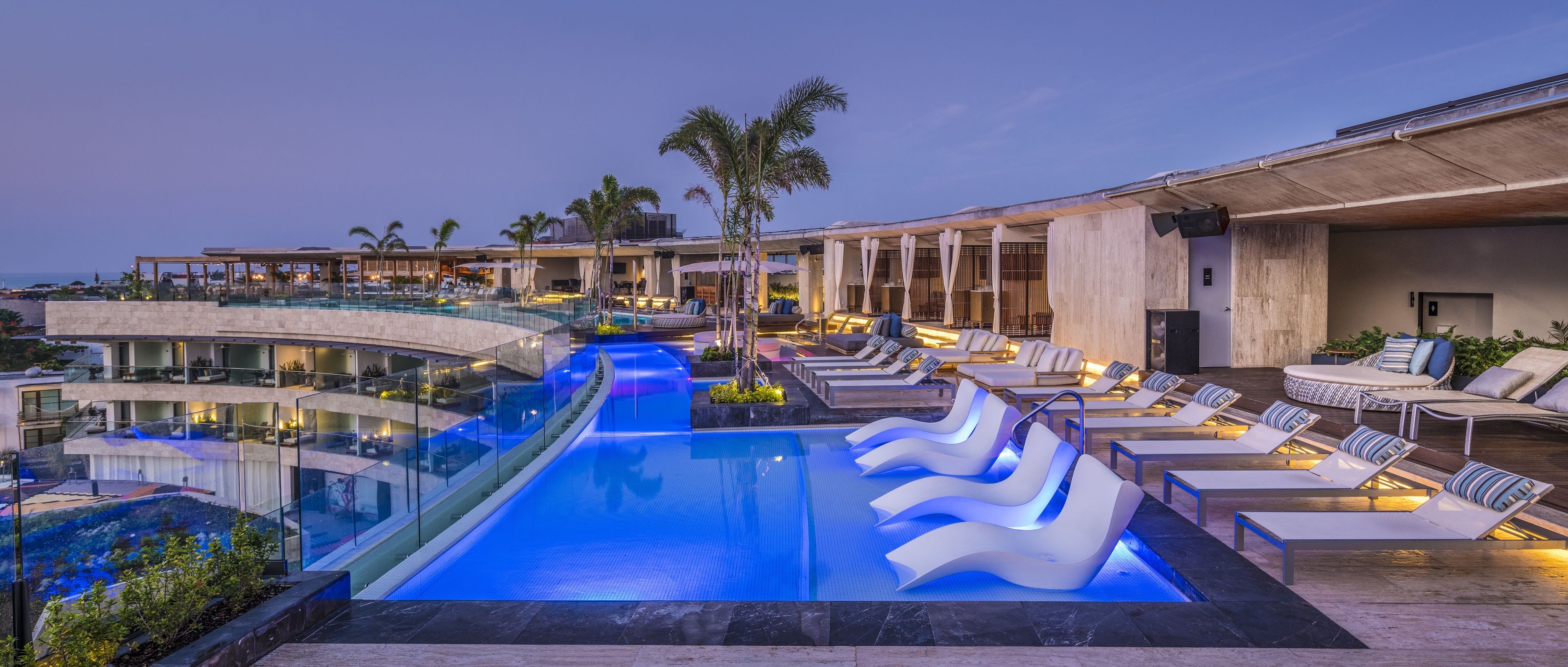 Et moderne resort med en stor, opvarmet pool, liggestole og havudsigt.
