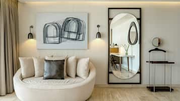 Una sala de estar moderna con un sofá redondo, un cuadro abstracto de gran tamaño, un espejo circular y una mesita con espejo.