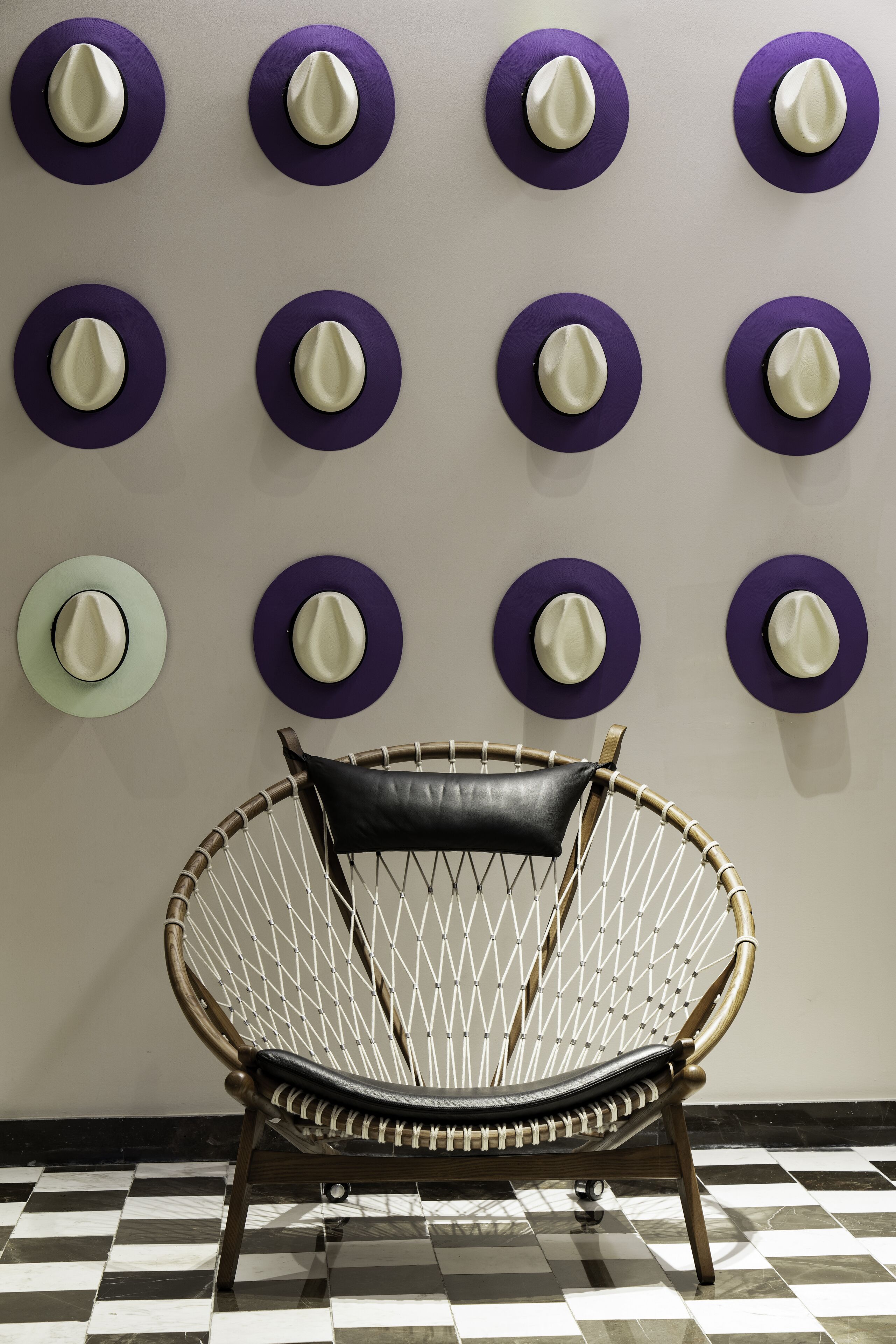 Una habitación con piso a cuadros y una silla frente a una pared decorada con adornos circulares.