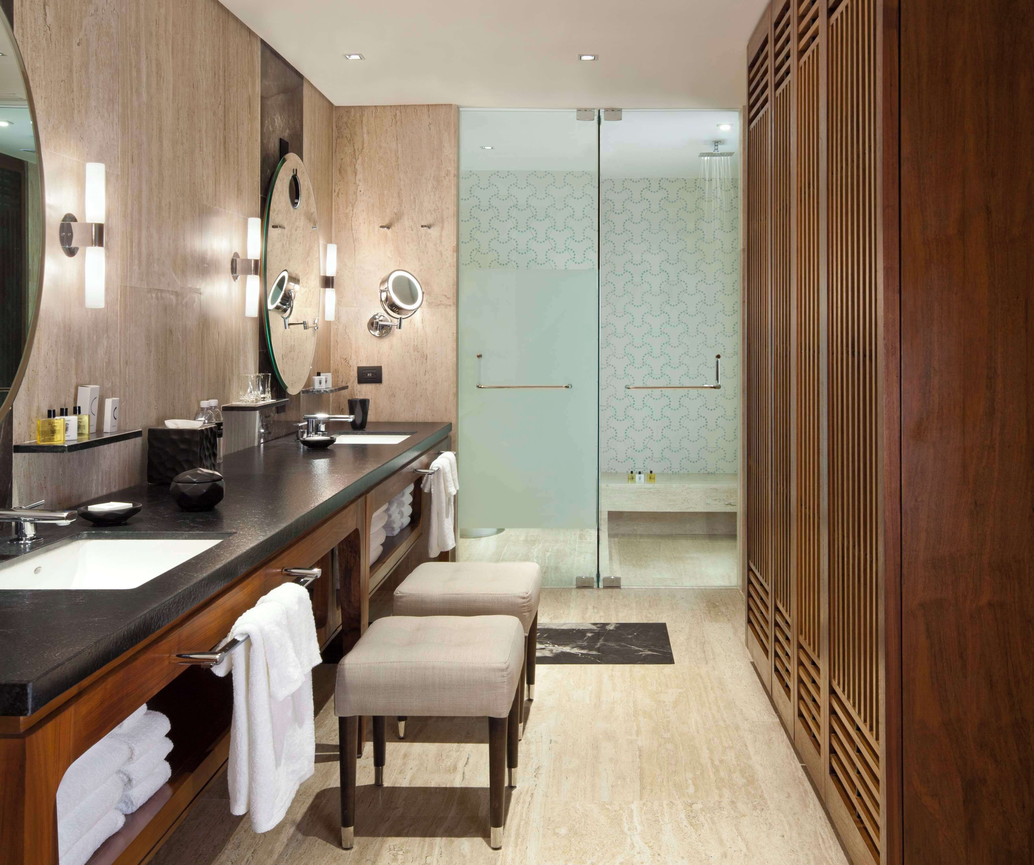 Une salle de bain moderne avec un meuble-lavabo en bois, deux vasques et une cabine de douche en verre.