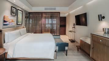 Una habitación de hotel moderna con una cama grande, un escritorio, un televisor y obras de arte en las paredes.