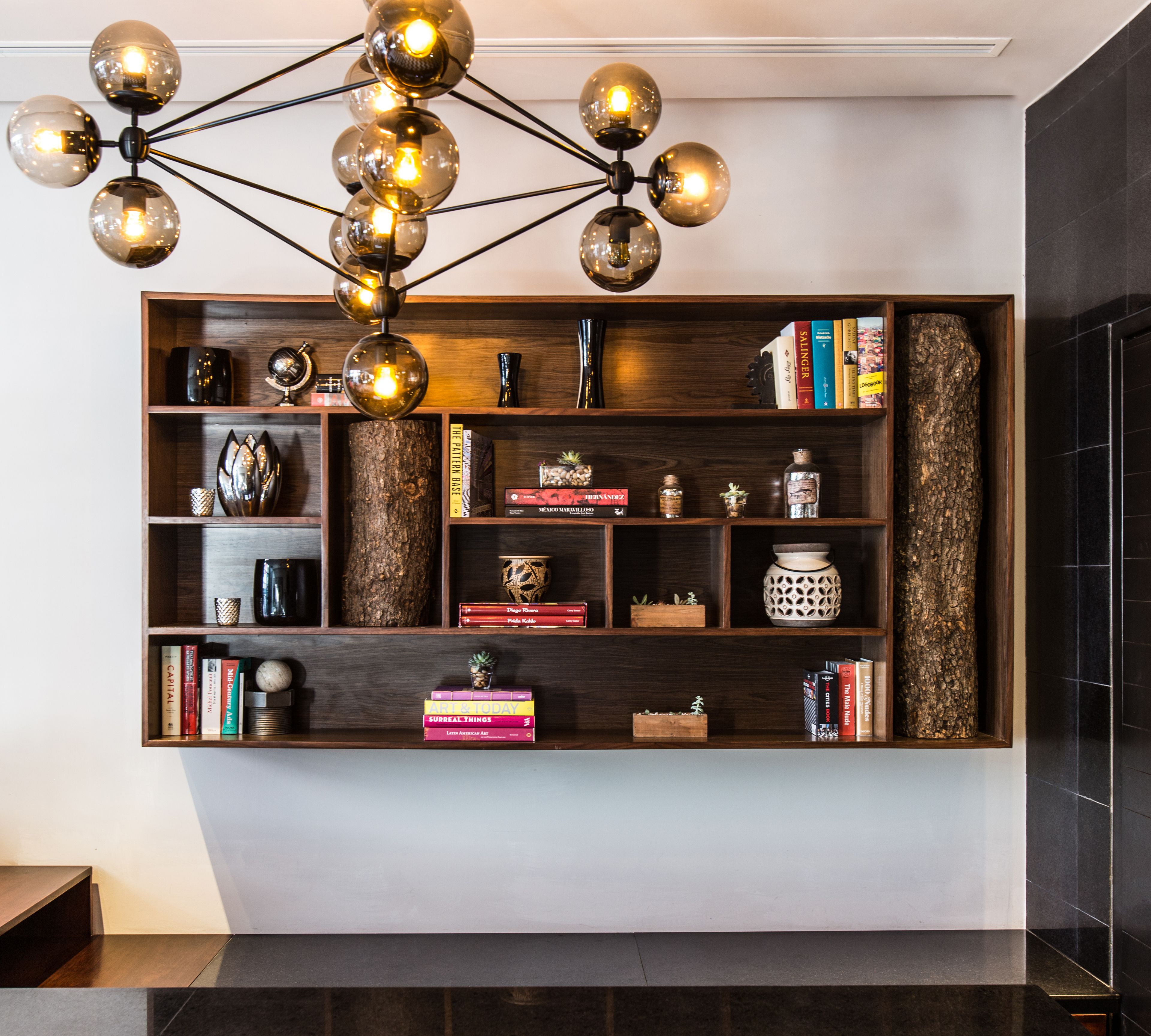 A modern interior with a wooden bookshelf, decorative items, and a unique spherical light fixture.